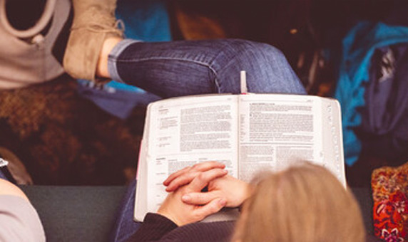 woman reading bible while sitting